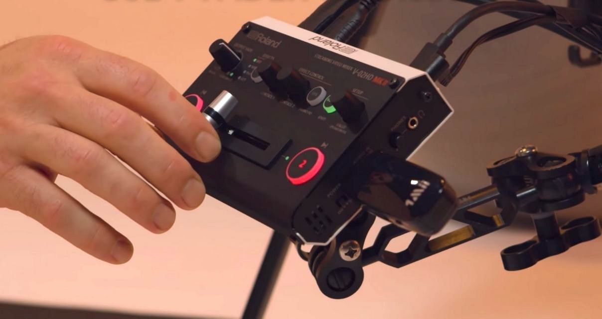 Man using fader to dissolve on the Roland V-02HD Mk II streaming video mixer