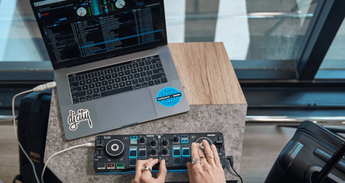 Person DJing on a table in the airport, using a controller and software