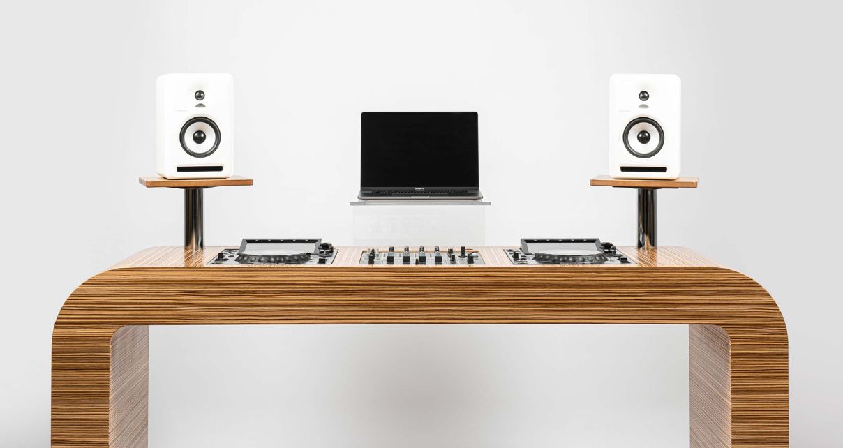 Booth view of the Classic Hoerboard style desk with pro DJ gear, a laptop and white monitors