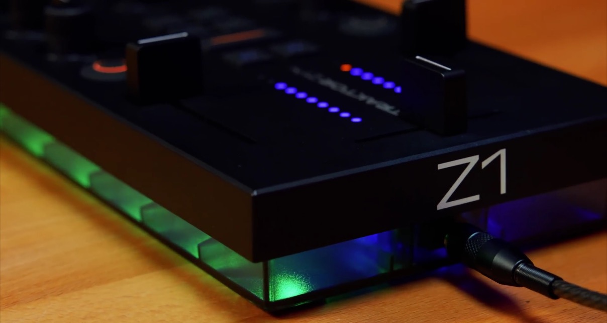 Rear view of the Traktor Z1 Mk2 on a wooden desk, displaying green and blue coloured lights inside the transparent base